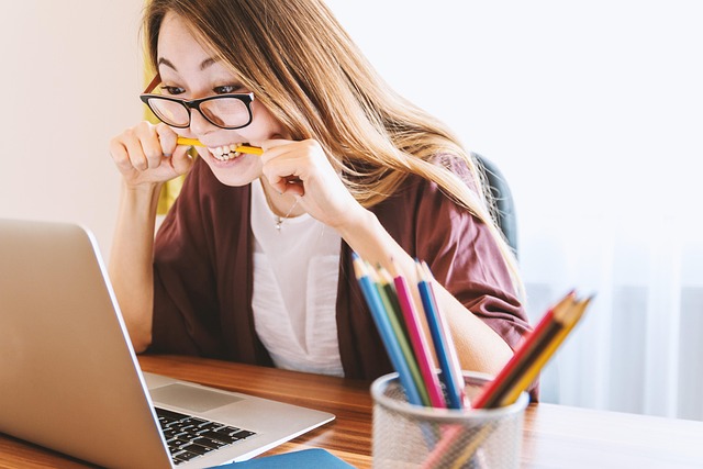 資格勉強に励む女性がノートとパソコンに向かう様子