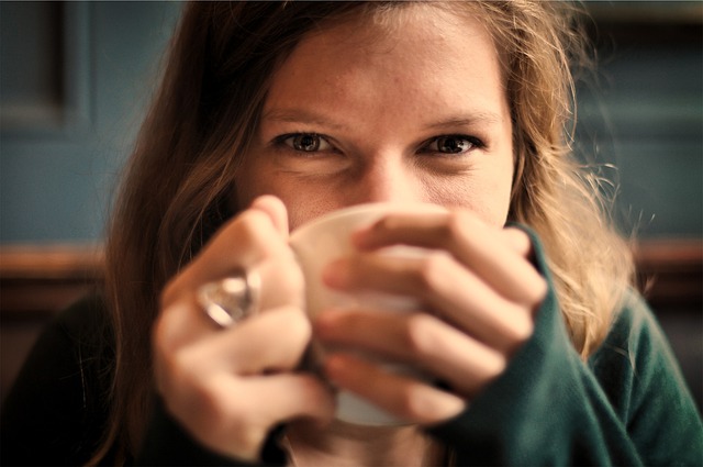 温かいコーヒーを飲みながら笑顔でリラックスする人のイメージ
