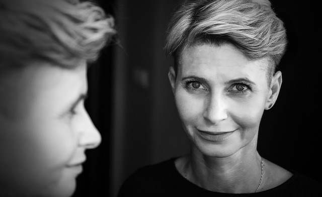 美顔器を使って笑顔で鏡を見る女性